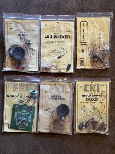 Six vintage EKI electronics project kits in sealed bags, including an LED blinker, robot blinker and nerve tester.